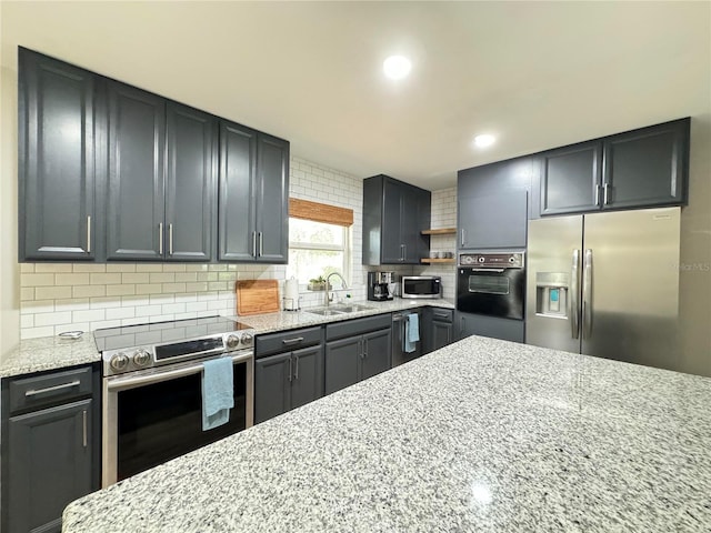 kitchen with stainless steel appliances, a sink, light stone counters, and tasteful backsplash