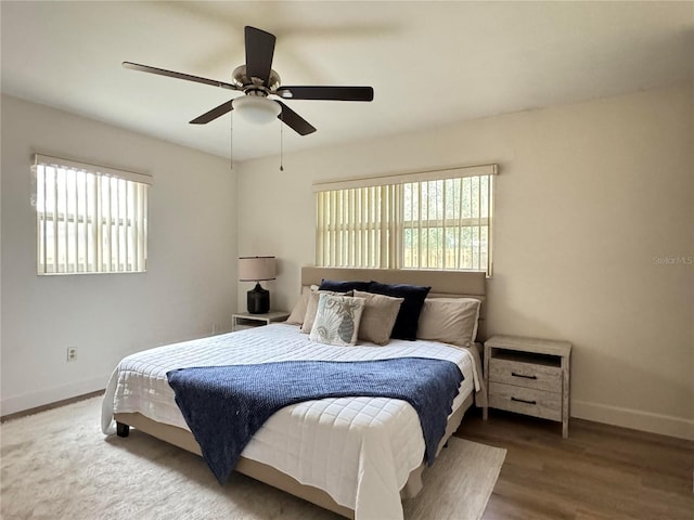 bedroom with a ceiling fan, baseboards, and wood finished floors