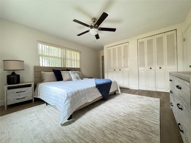 bedroom featuring ceiling fan, dark wood-style flooring, and two closets