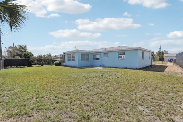 rear view of house with fence and a lawn