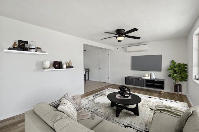 living room featuring ceiling fan, an AC wall unit, wood finished floors, and baseboards