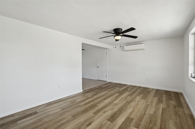 empty room with a ceiling fan, baseboards, an AC wall unit, and wood finished floors