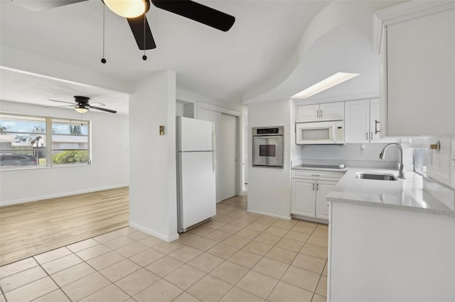 kitchen with backsplash, light tile patterned flooring, a sink, white cabinetry, and white appliances