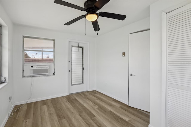 unfurnished bedroom featuring cooling unit, wood finished floors, a ceiling fan, and baseboards