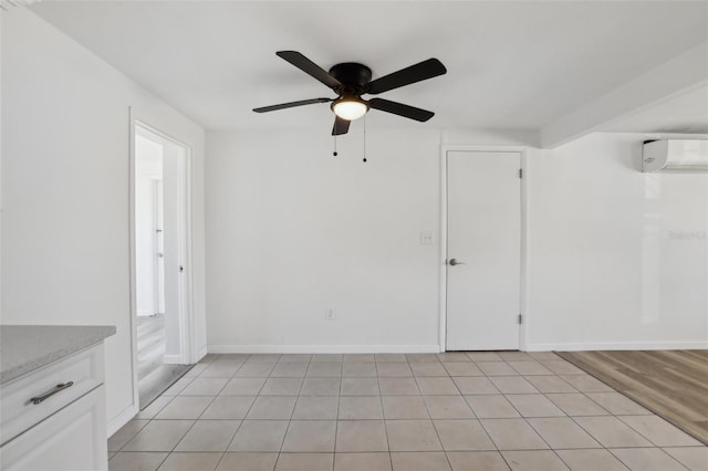 spare room featuring ceiling fan, baseboards, and an AC wall unit