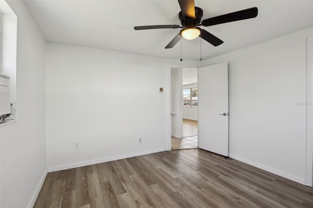 empty room featuring ceiling fan, baseboards, and wood finished floors