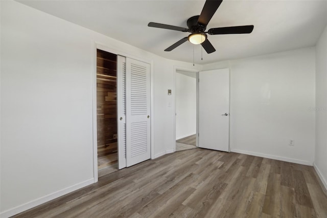 unfurnished bedroom featuring a closet, wood finished floors, a ceiling fan, and baseboards