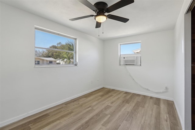 empty room featuring cooling unit, baseboards, ceiling fan, and light wood finished floors