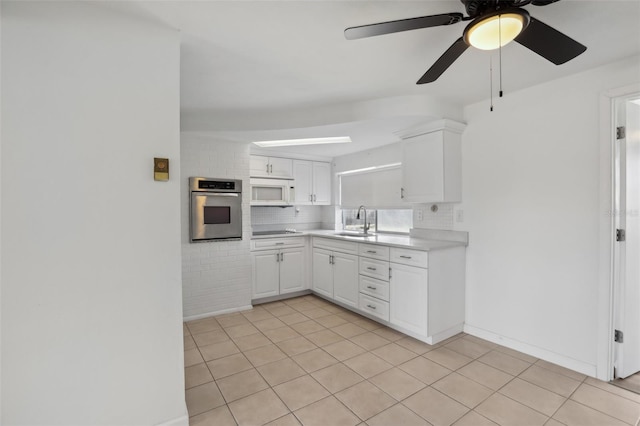 kitchen featuring light countertops, white microwave, white cabinets, stainless steel oven, and a sink