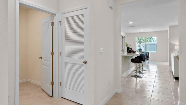 hall with light tile patterned floors, baseboards, and recessed lighting