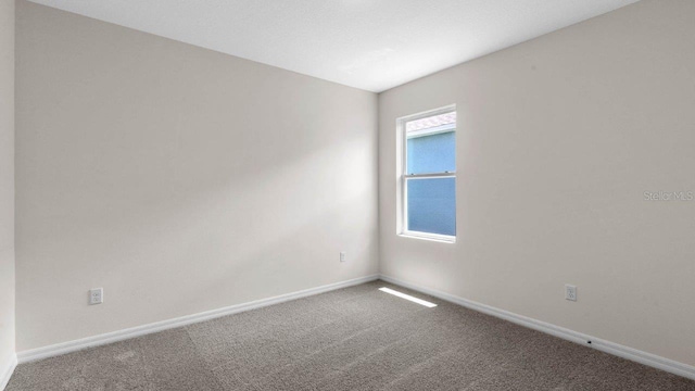 carpeted spare room featuring baseboards