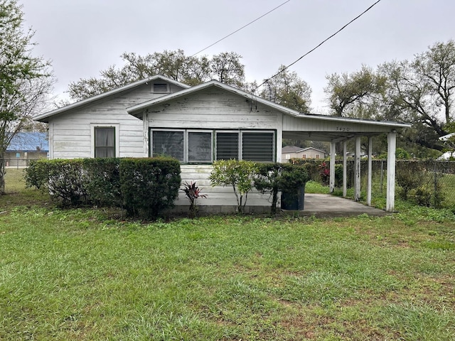 view of front of home with an attached carport, fence, and a front lawn