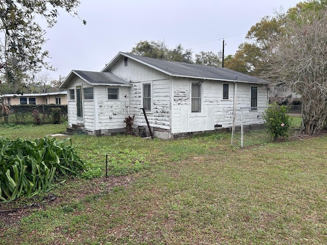 back of property with entry steps, fence, and a yard