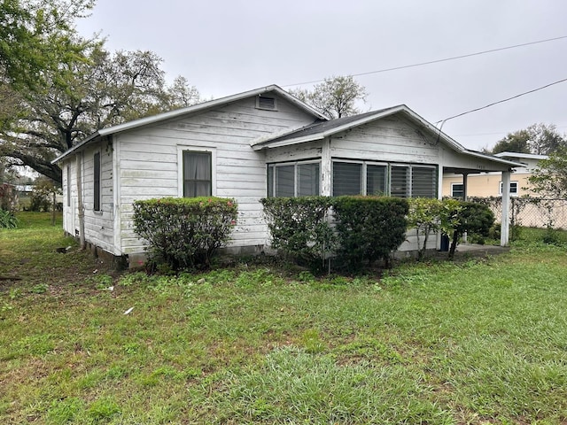 view of home's exterior featuring a lawn and fence