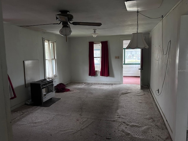 unfurnished living room with ceiling fan, carpet floors, baseboards, and heating unit