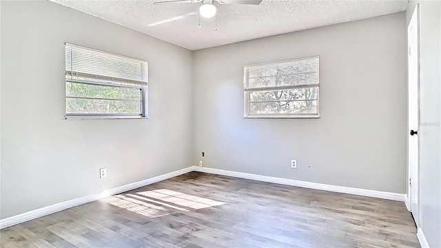 spare room featuring baseboards, wood finished floors, a textured ceiling, and ceiling fan