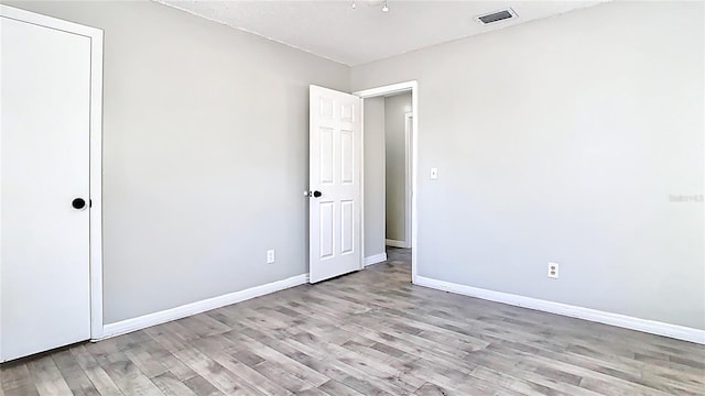 unfurnished bedroom featuring wood finished floors, visible vents, and baseboards