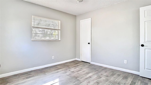 unfurnished bedroom with wood finished floors, baseboards, ceiling fan, a closet, and a textured ceiling