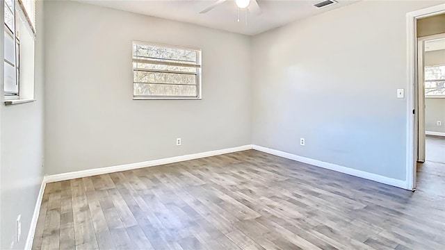 empty room with wood finished floors, a ceiling fan, and baseboards