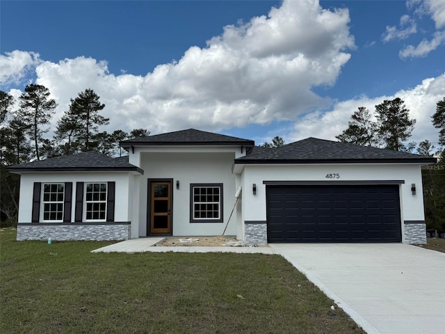 prairie-style house featuring stucco siding, an attached garage, a front yard, stone siding, and driveway