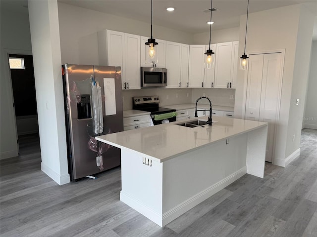 kitchen featuring appliances with stainless steel finishes, light countertops, light wood-style floors, white cabinetry, and a sink