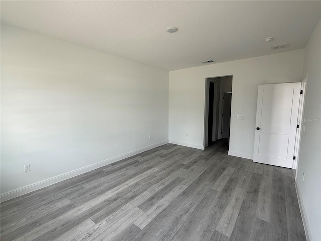 unfurnished bedroom featuring visible vents, baseboards, and wood finished floors