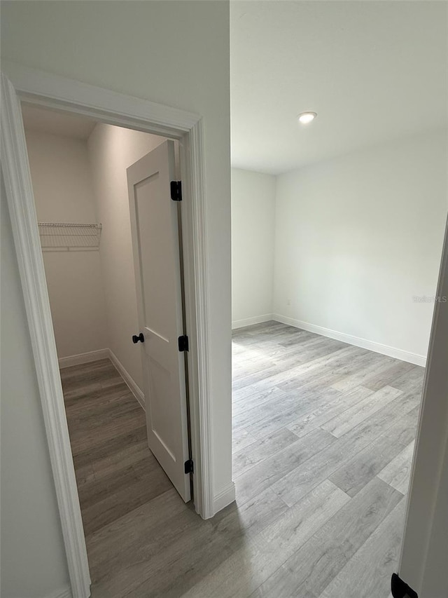 hall featuring light wood-style floors, baseboards, and recessed lighting