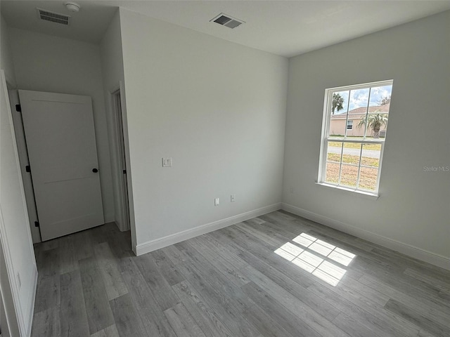 unfurnished room featuring wood finished floors, visible vents, and baseboards