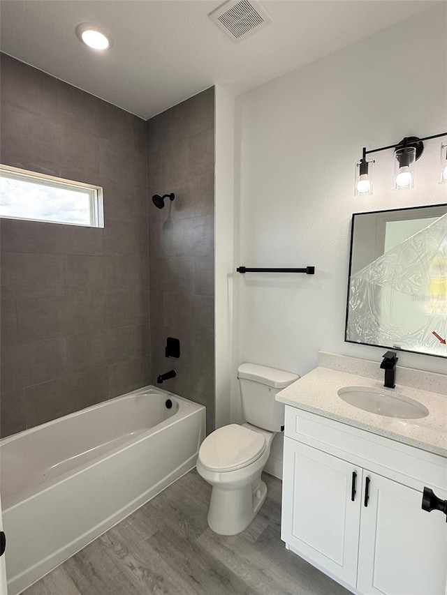 full bath featuring visible vents, shower / bathing tub combination, toilet, vanity, and wood finished floors