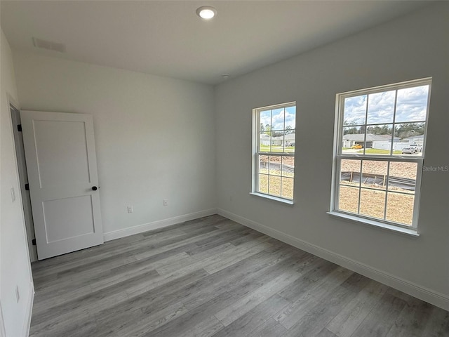 empty room with recessed lighting, baseboards, and wood finished floors