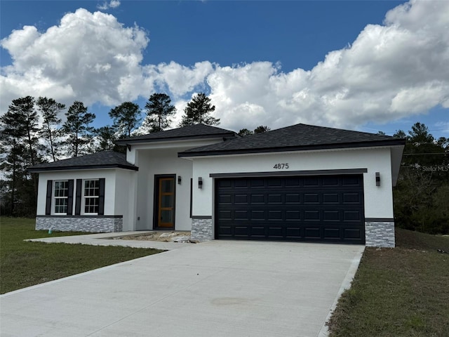 prairie-style house with a garage, stone siding, concrete driveway, stucco siding, and a front yard