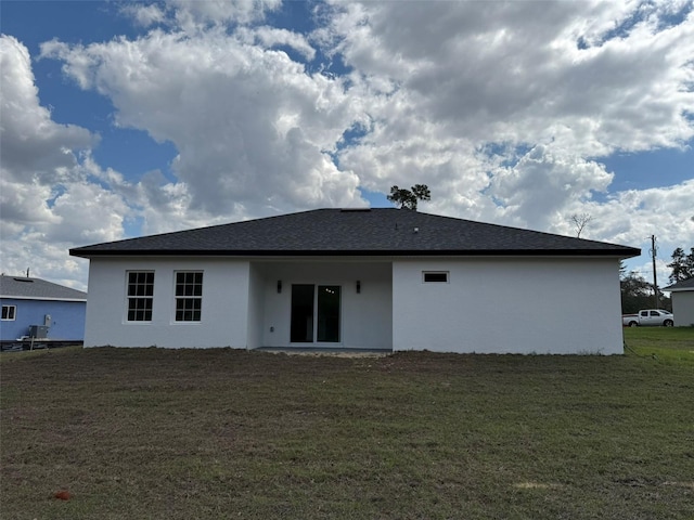 rear view of property with a lawn and stucco siding