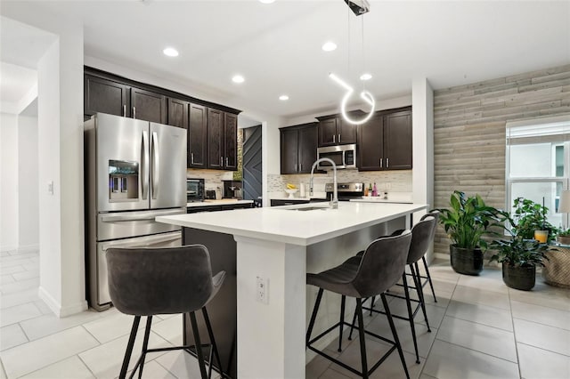 kitchen with light countertops, appliances with stainless steel finishes, a breakfast bar area, and a sink