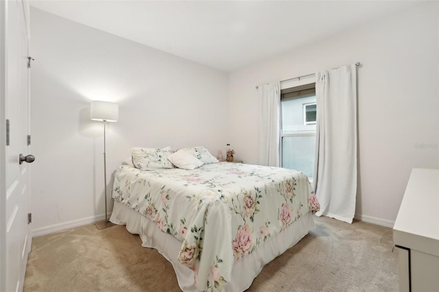 bedroom featuring light colored carpet and baseboards