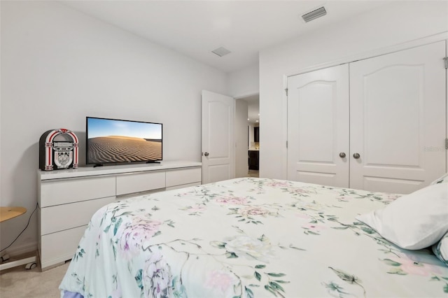 bedroom with a closet, visible vents, and light carpet