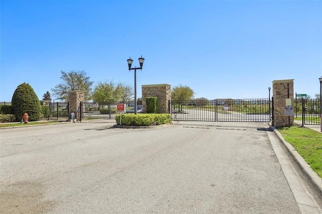 view of road with curbs, a gated entry, street lighting, and a gate