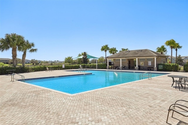 community pool with a patio and fence