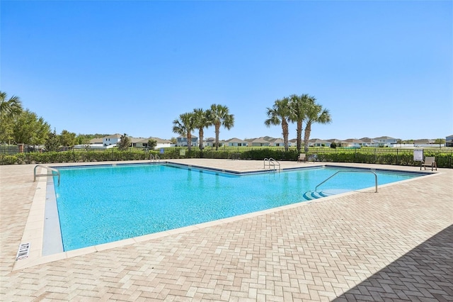 community pool featuring a patio, fence, and a residential view