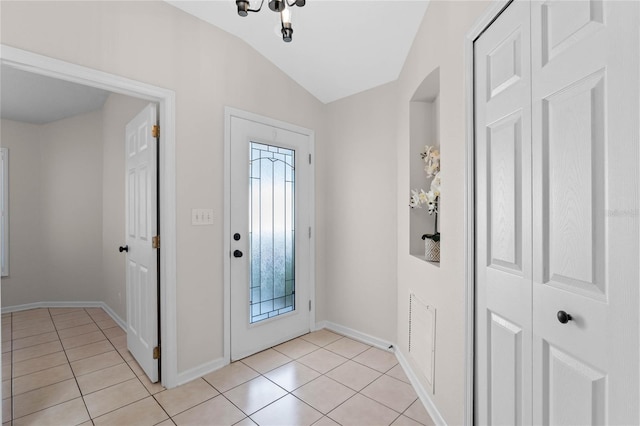 foyer with vaulted ceiling, baseboards, and light tile patterned floors