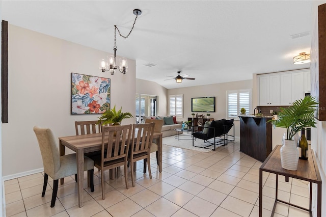 dining room with light tile patterned floors, vaulted ceiling, ceiling fan with notable chandelier, and visible vents