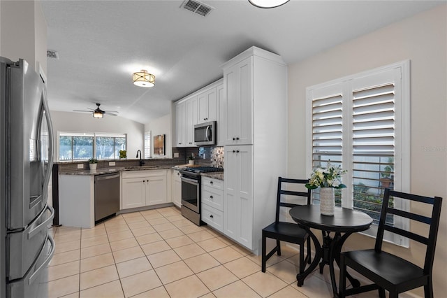 kitchen with light tile patterned floors, stainless steel appliances, visible vents, and white cabinetry