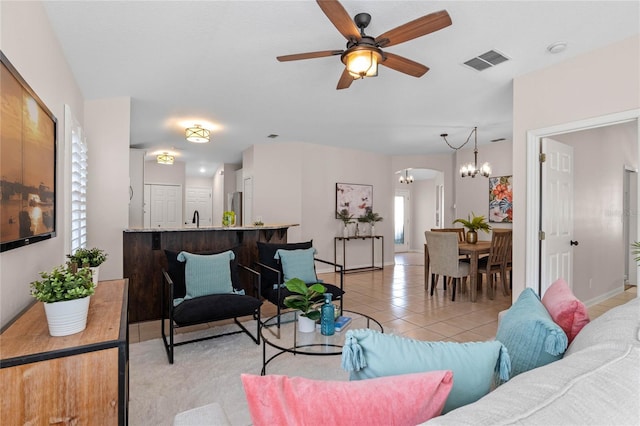 living room with arched walkways, light tile patterned floors, visible vents, baseboards, and ceiling fan with notable chandelier