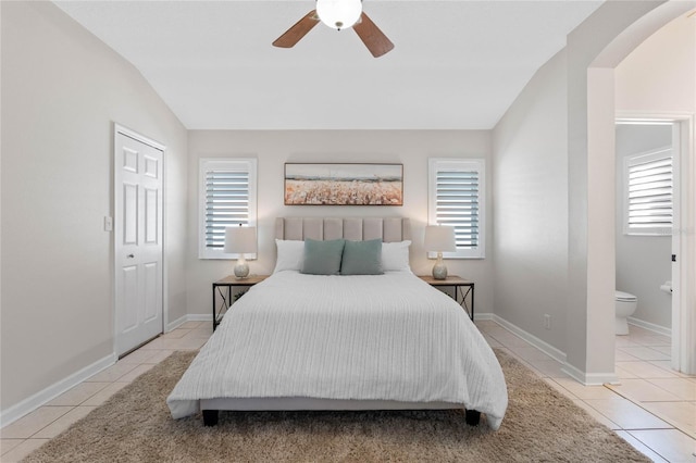 tiled bedroom featuring lofted ceiling, multiple windows, and arched walkways