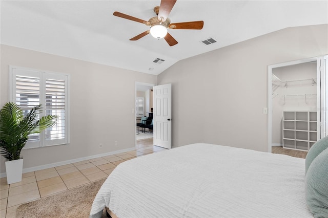 bedroom with lofted ceiling, light tile patterned floors, visible vents, and baseboards