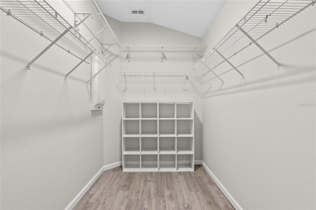 walk in closet featuring lofted ceiling, visible vents, and wood finished floors