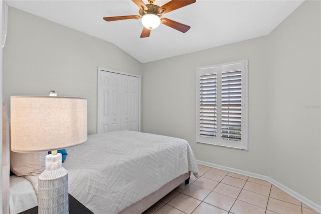 tiled bedroom with vaulted ceiling, a closet, a ceiling fan, and baseboards