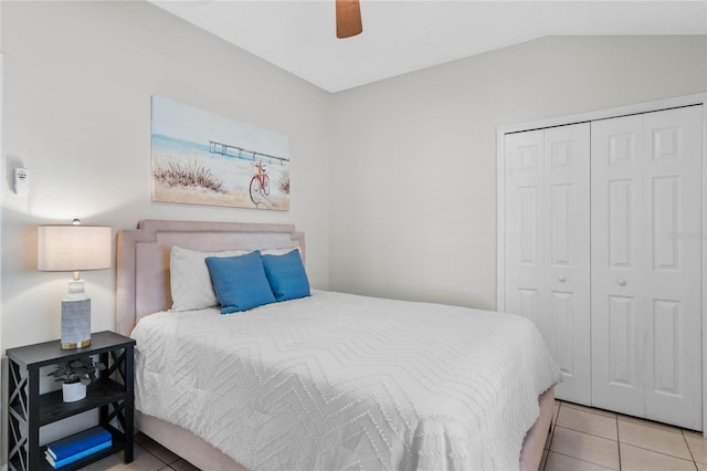 tiled bedroom with vaulted ceiling, a closet, and a ceiling fan