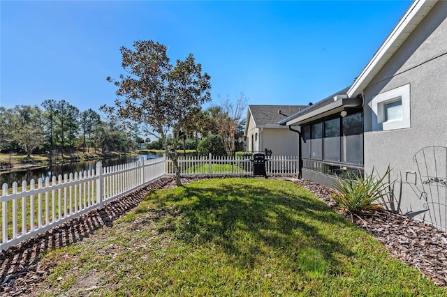 view of yard with a sunroom, a fenced backyard, and a water view