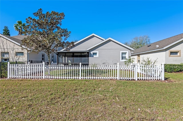 view of front facade with a front lawn, fence, a sunroom, and stucco siding