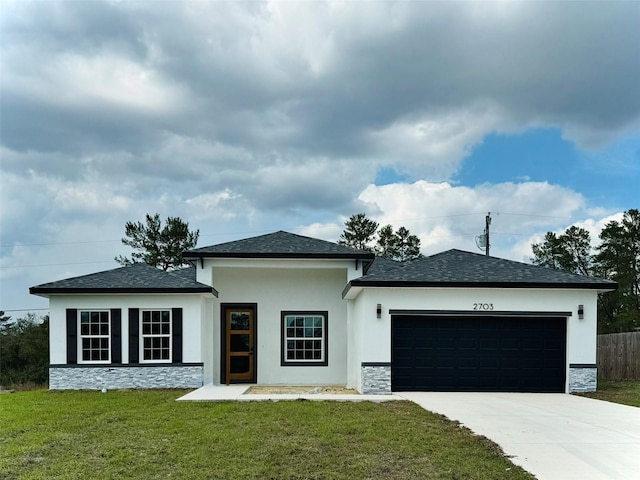 prairie-style home with an attached garage, stone siding, a front yard, and driveway